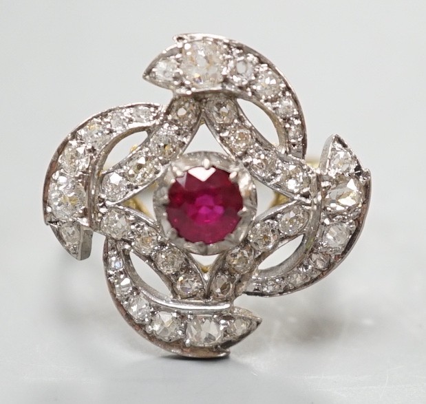 A yellow metal, ruby and diamond cluster set dress ring, in a pierced scroll setting, size O, gross weight 6 grams.